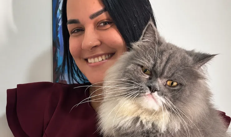 Tutora sorridente com um gato persa no colo